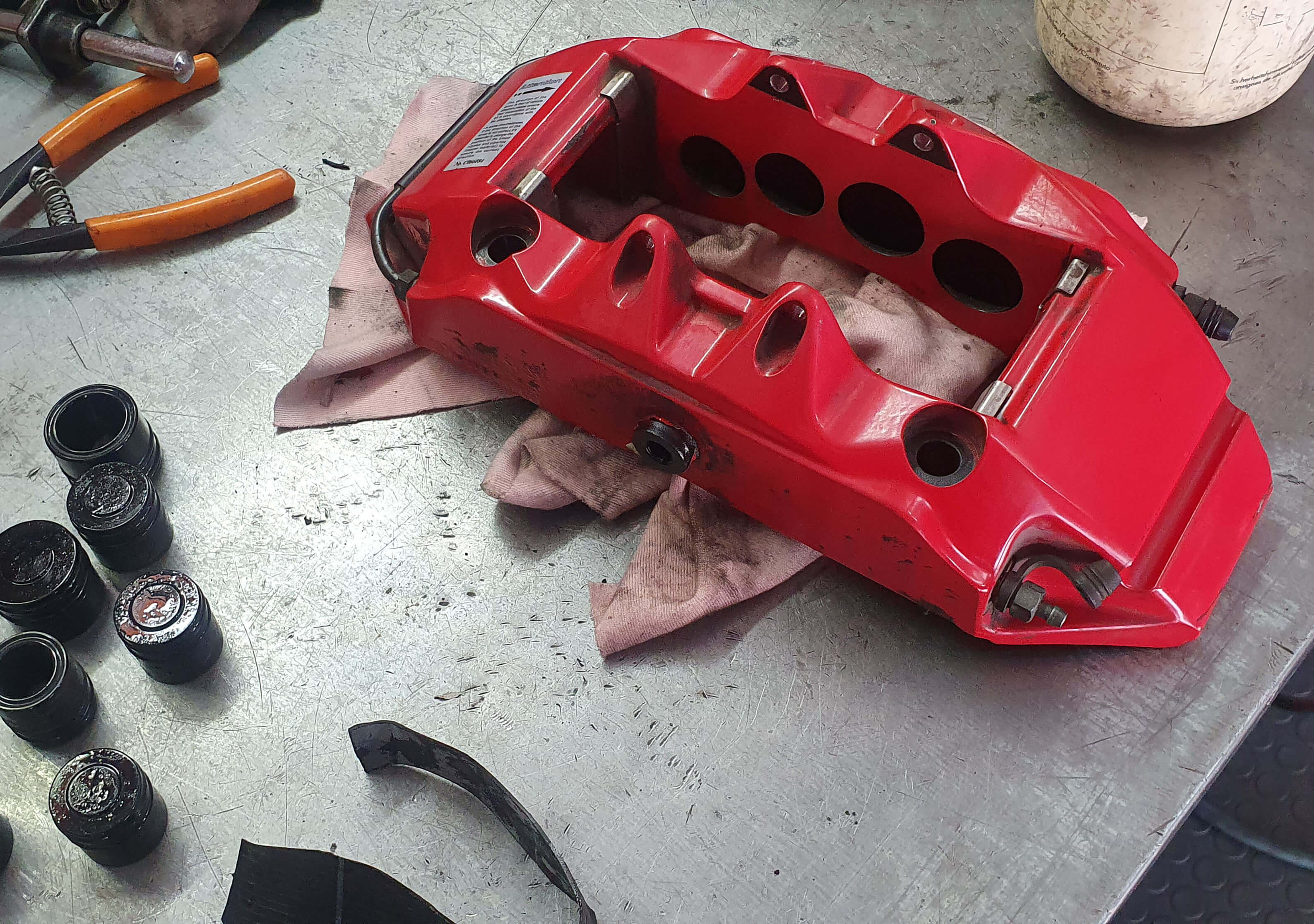 Κόκκινη εξαπίστονη δαγκάνα racing. Η δαγκάνα είναι λυμμένη και τοποθετημένη πάνω στον πάγκο εργασίας.