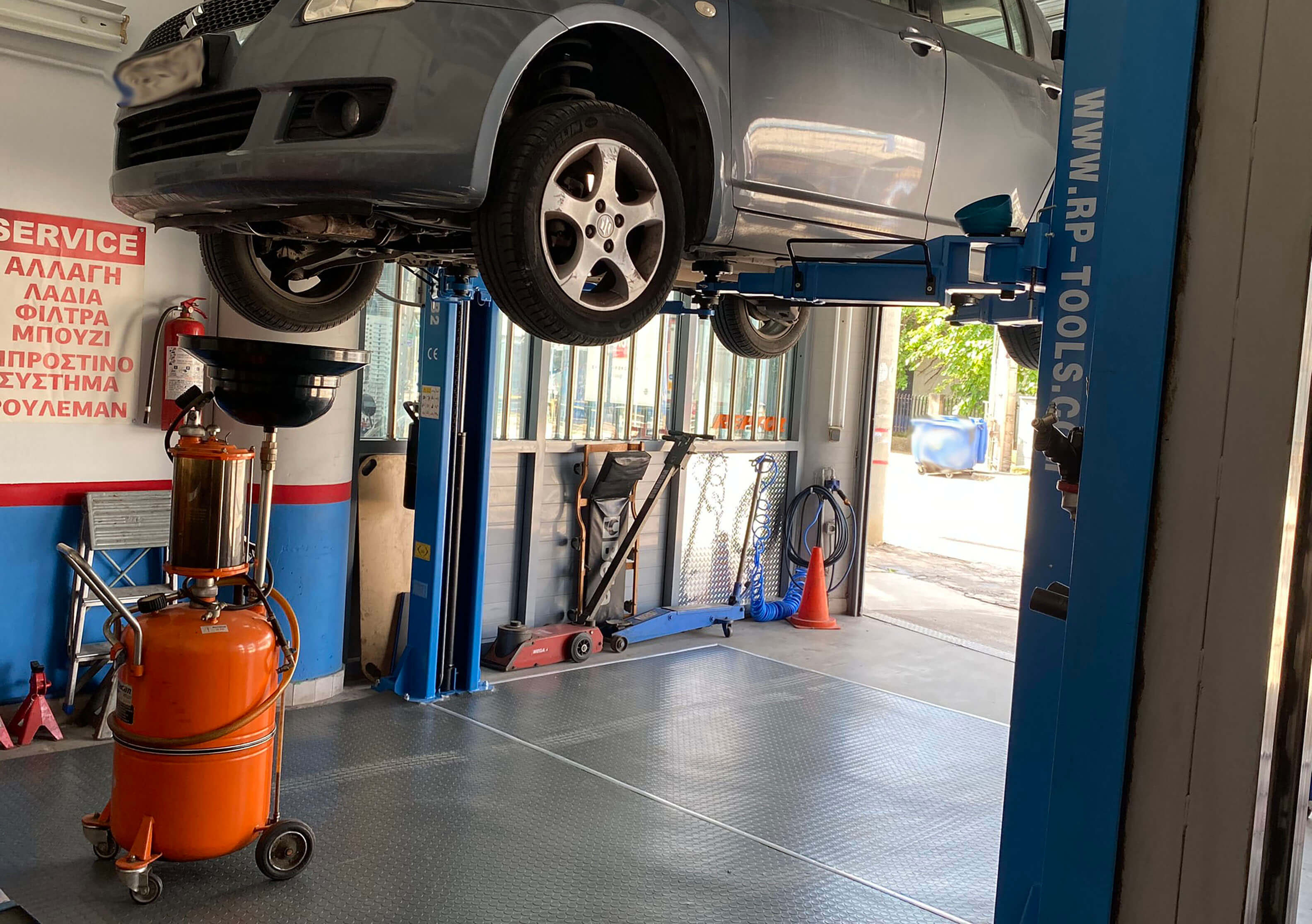 Αλλαγή λαδιών σε αυτοκίνητο μάρκας SUZUKI. Το αυτοκίνητο είναι ανυψωμένο με τη βοήθεια αναβατορίου και απο κάτω είναι τοποθετημένος ο συλλέκτης λαδιού.