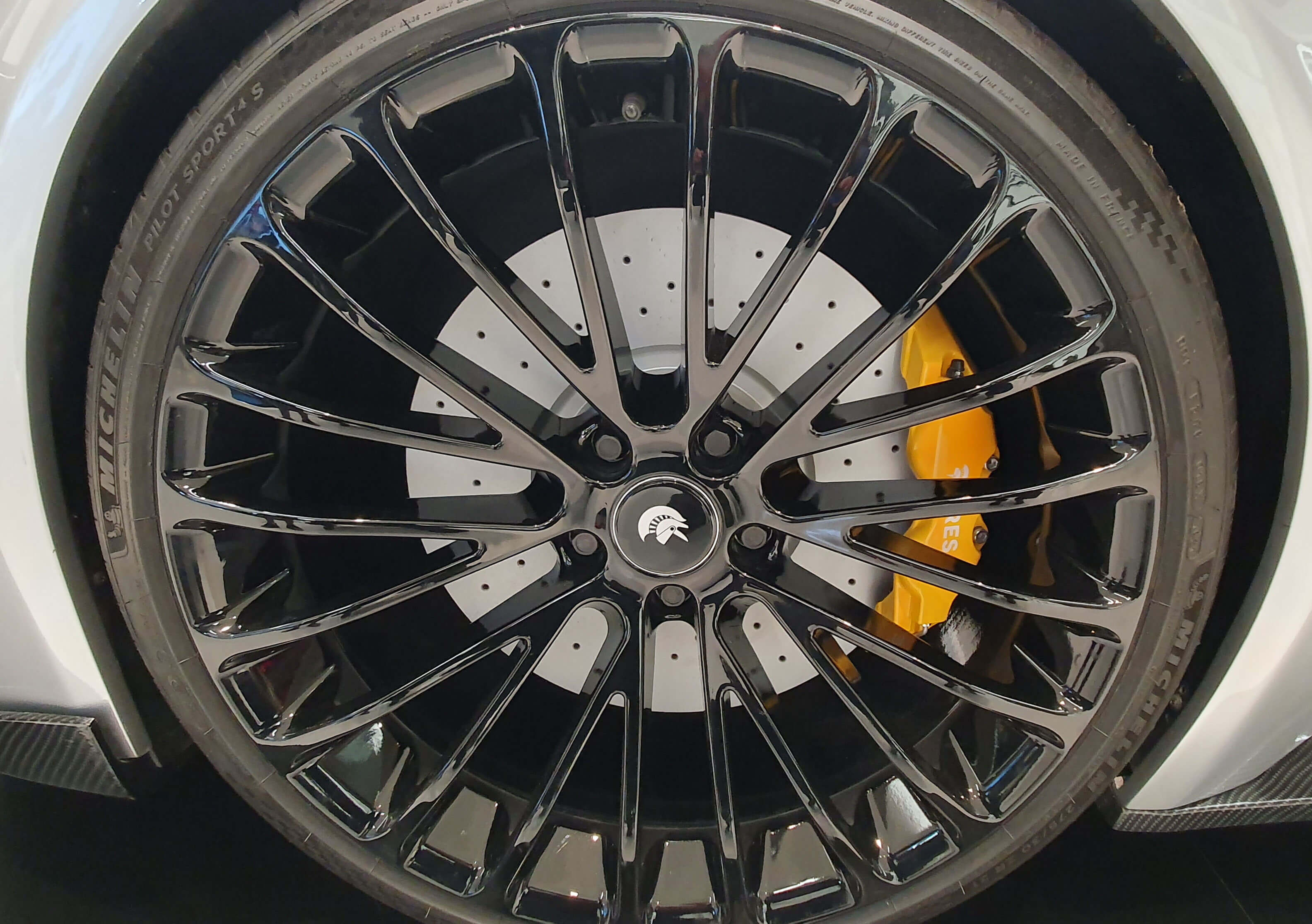 Μια ρόδα αυτοκινήτου σπορ αυτοκινήτου καταλαμβάνει όλη την εικόνα. Ανάμεσα στις ακτίνες της ζάντας φαίνεται η δισκόπλακα και η δαγκάνα χρώματος κίτρινο.