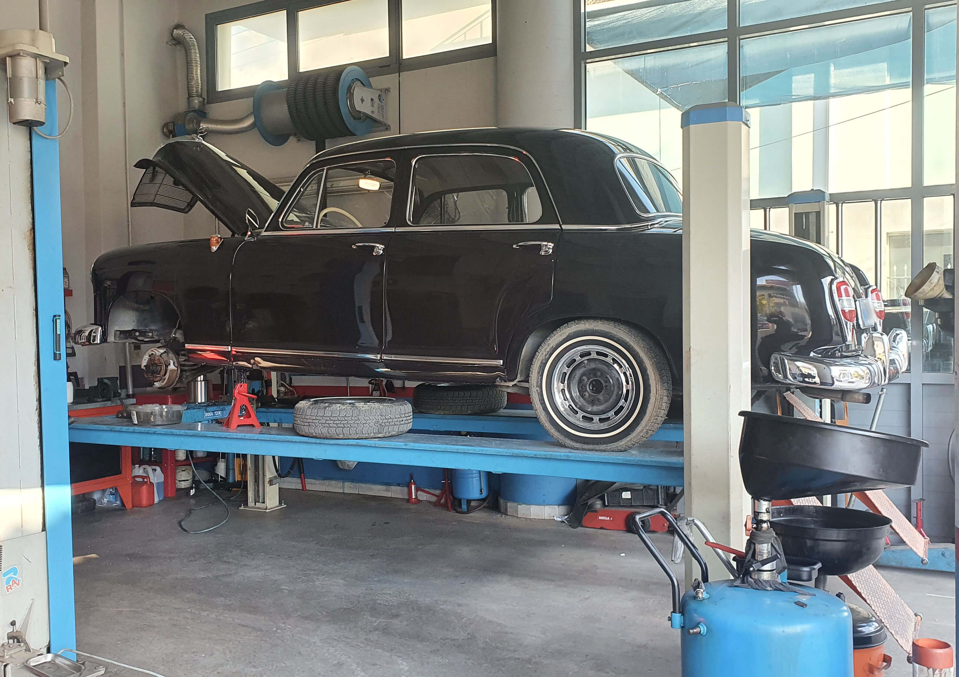 Μαύρο αυτοκίνητο αντίκα πάνω στο αναβατόριο. Η μπροστινή ρόδα έχει αφαιρεθεί για να επισκευαστεί το φρένο.